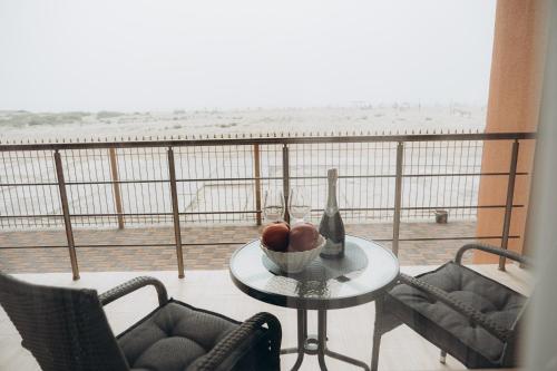 a table with a bottle and a bowl of fruit on a balcony at Три Слона in Zatoka