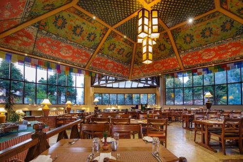 un restaurante con mesas y sillas de madera y un gran techo en Club Himalaya, by ACE Hotels, en Nagarkot