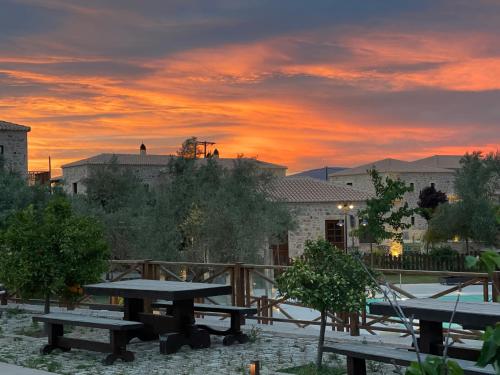 a group of picnic tables with a sunset in the background at Mystras Grand Palace Resort & Spa in Mystras