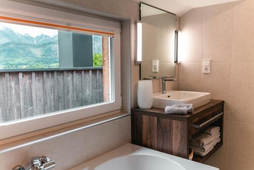bagno con vasca, lavandino e finestra di CHICLIVING Appartements a St. Wolfgang