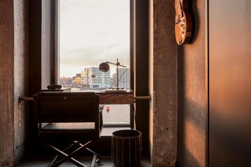 a chair in front of a window with a view of a city at Sir Adam Hotel, part of Sircle Collection in Amsterdam