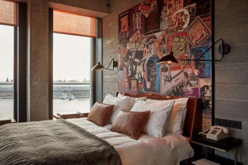 a bedroom with a large bed with a wall covered in posters at Sir Adam Hotel in Amsterdam