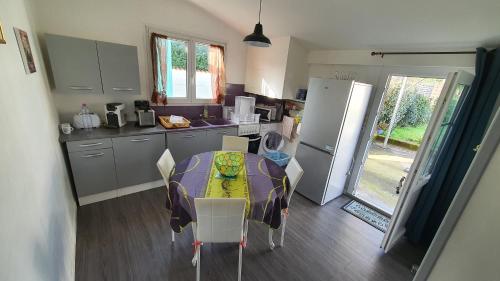 a kitchen with a table with chairs and a refrigerator at Entre port et plages in La Tremblade