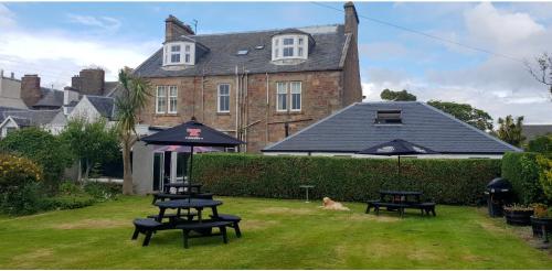 a house with three picnic tables in the yard at Ardshiel Hotel in Campbeltown