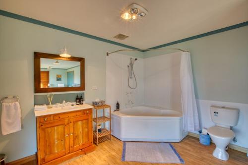 een badkamer met een bad, een wastafel en een toilet bij Beach Side Bay Of Fires in Binalong Bay