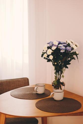 a table with two cups and a vase with flowers at BOOGIE Home Kamienica Łódzka in Łódź
