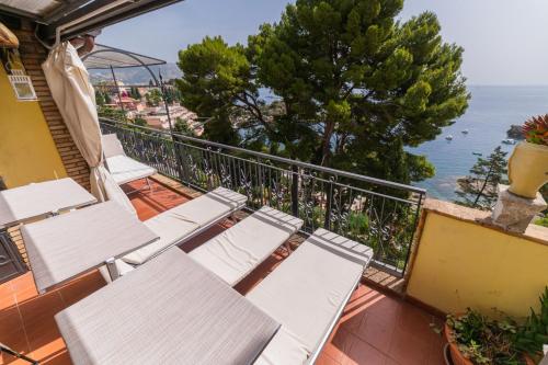 a balcony with white chairs and a view of the ocean at ToviMar Apartments in Taormina