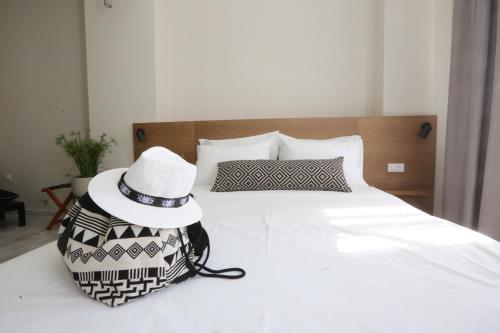 a person wearing a hat sitting on a bed at OIKO MINI SUITES in Ermoupoli