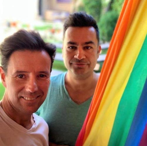 two men are standing next to a rainbow flag at La Casona de Castilnovo - Gay Men Only in Valdesaz