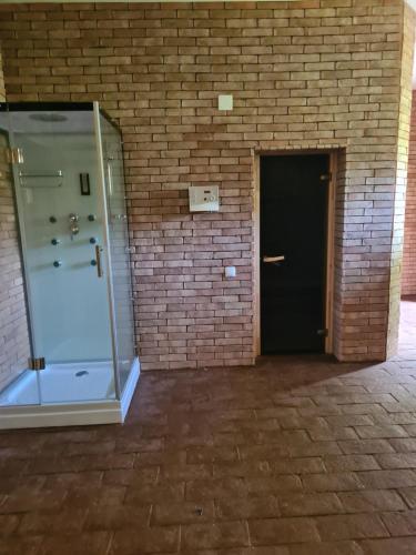 a glass shower in a brick building with a black door at Vila Vraja Muntelui in Moieciu de Jos