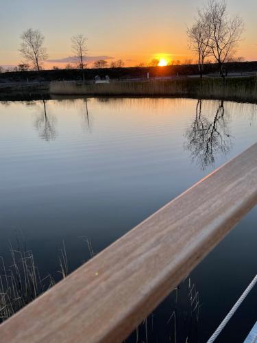 eine Holzbrücke über einen Wasserkörper bei Sonnenuntergang in der Unterkunft Marsk Camp in Skærbæk