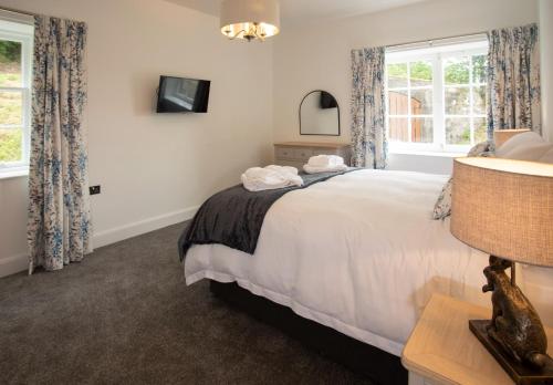 a bedroom with a large white bed and two windows at Laundry Cottage: Drumlanrig Castle in Thornhill