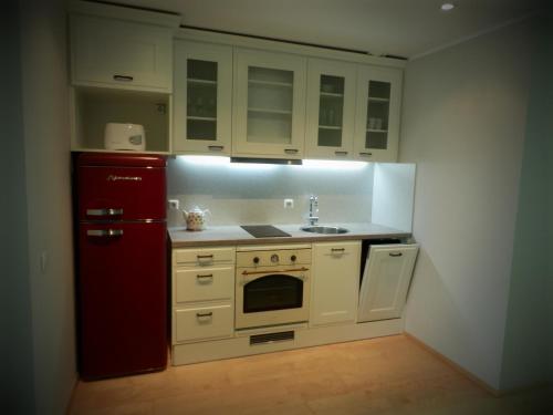 La cuisine est équipée de placards blancs et d'un réfrigérateur rouge. dans l'établissement Apartment Suvekorter Aida, à Pärnu