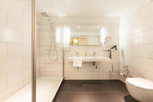a bathroom with a shower and a toilet and a sink at Sure Hotel by Best Western Muenchen Hauptbahnhof in Munich