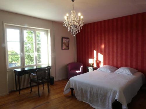 a bedroom with a bed and a desk and a chandelier at Les Jardins de Xanton in Xanton-Chassenon