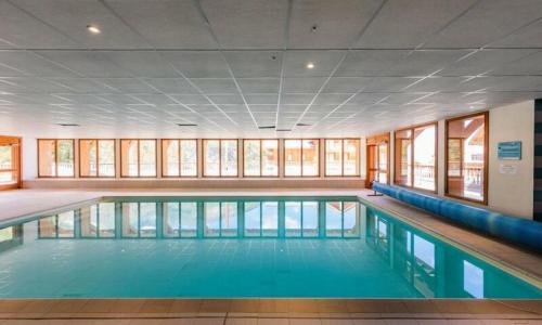 une grande piscine avec de l'eau bleue dans un immeuble dans l'établissement L'Oural, aux Orres