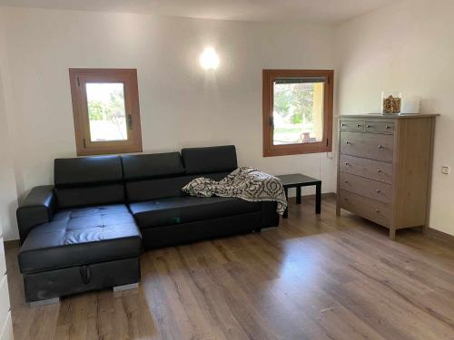 a living room with a black couch and a dresser at Can ventura alojamiento entero in La Vall de Bianya