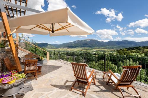 a patio with chairs and an umbrella and mountains at Cal Cassi - Suite de muntanya in Ger
