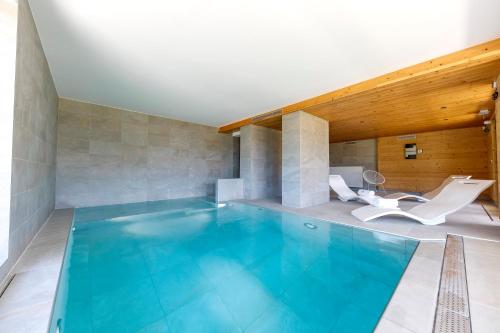 una gran piscina con 2 sillas blancas en una habitación en AUBERGE DES GLIERES en Thorens-Glières
