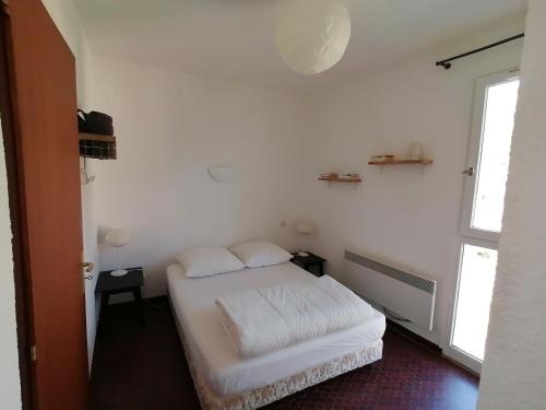une chambre blanche avec un lit et une fenêtre dans l'établissement Impasse des Rhododendrons, Résidence 