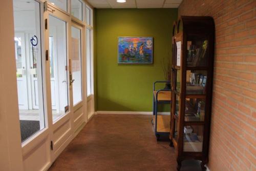 a hallway with a green wall and a book shelf at Hostel Herning in Herning