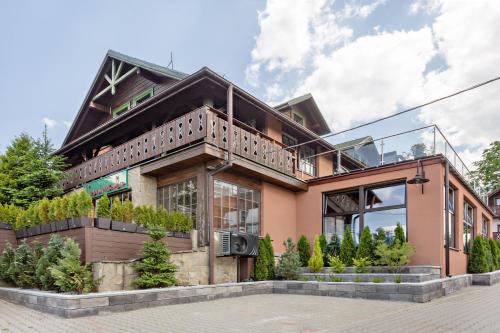 a house with a balcony on top of it at Osrodek Wypoczynkowy Lesniczówka & Elias SPA in Istebna