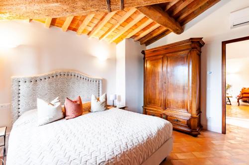 a bedroom with a white bed and a wooden cabinet at Villa Boccaccio in San Gimignano
