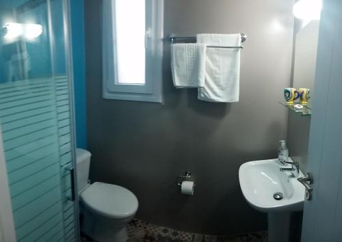 a bathroom with a white toilet and a sink at Zeras Apartments in Adamas