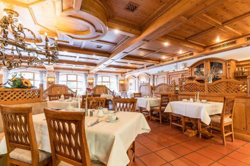 a restaurant with tables and chairs and a chandelier at Hotel Blaue Gams ***S in Ettal