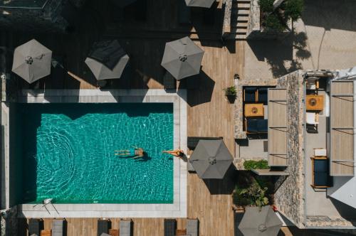 a person swimming in a swimming pool with umbrellas at Seascape Luxury Residences in Agia Pelagia
