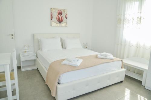 a white bedroom with a bed with two towels on it at Zeras Apartments in Adamas