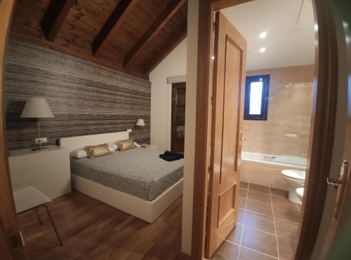 1 dormitorio con 1 cama y baño con bañera en Casa Orbil, en Villanúa