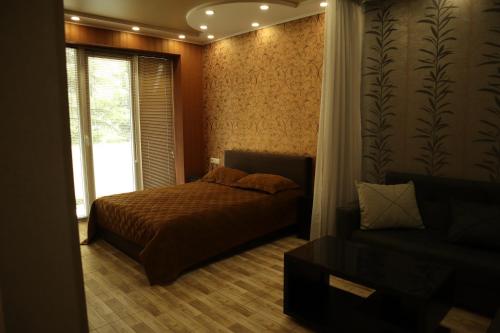 een slaapkamer met een bed, een raam en een bank bij Comfort Lux in Tbilisi City