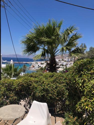 a palm tree and a table and chairs on a beach at Rania Apartments Sea View in Mýkonos City