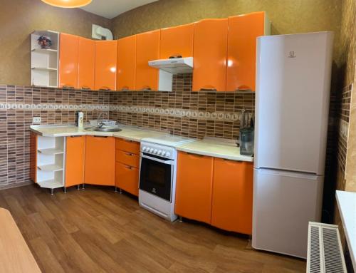 a kitchen with orange cabinets and a white refrigerator at Квартира в новострое in Odesa