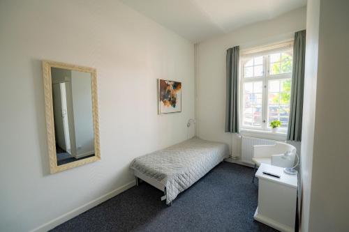 ein kleines Schlafzimmer mit einem Bett und einem Spiegel in der Unterkunft Det Gamle Posthus in Rønne