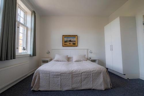 a white bedroom with a bed and a window at Det Gamle Posthus in Rønne