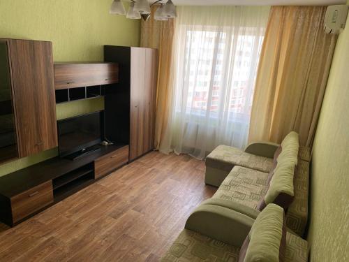 een woonkamer met een bank en een televisie bij Квартира в новострое in Odessa