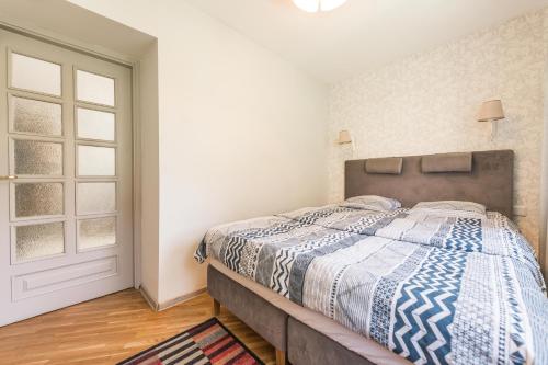 een slaapkamer met een bed met een blauw en wit dekbed bij Taikos Hill Apartamentai Nidoje in Nida