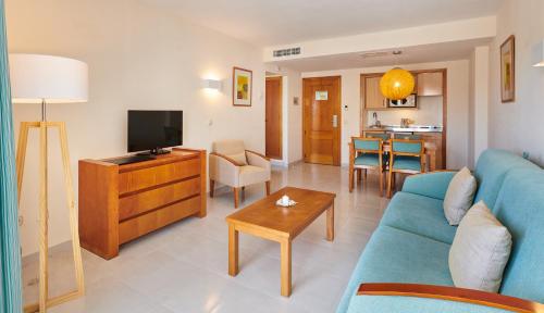 a living room with a blue couch and a tv at Hipotels Coma Gran in Sa Coma
