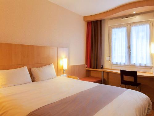 um quarto de hotel com uma cama grande e uma janela em ibis Alençon em Alençon