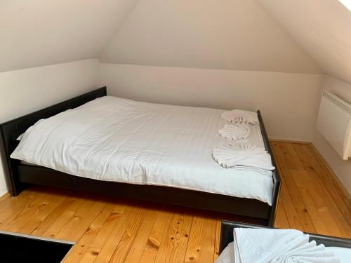 a bedroom with a bed with white sheets and wooden floors at Vila Darija Zlatar - studio apartman br. 3 in Nova Varoš
