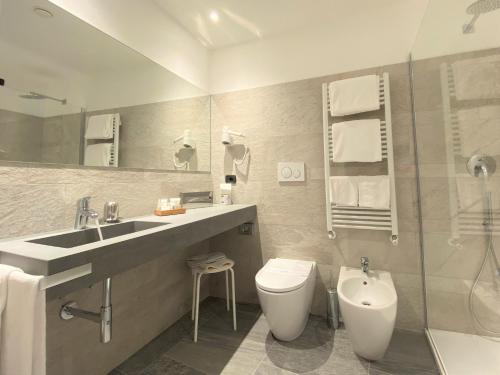a bathroom with a sink and a toilet and a mirror at Hotel Tirreno in Spotorno