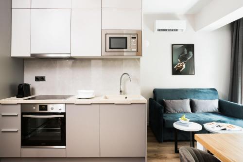 a kitchen with white cabinets and a blue couch at LUX&EASY Athens Downtown Apartments in Athens