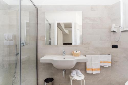 a white bathroom with a sink and a shower at Hotel Tirreno in Spotorno