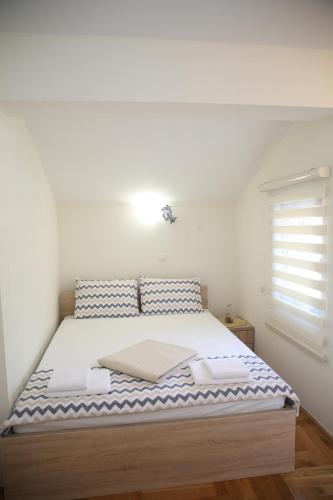 een slaapkamer met een groot bed met witte lakens bij Apartmani Dijana 2 in Kotor
