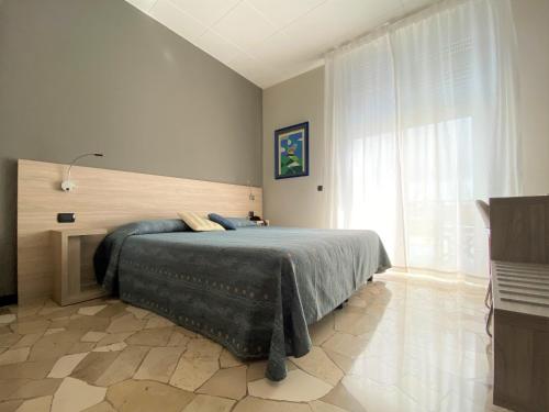 a bedroom with a bed and a large window at Hotel Tirreno in Spotorno