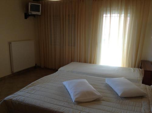 a bedroom with two beds with white sheets and a window at Guesthouse Lamprini in Neochori