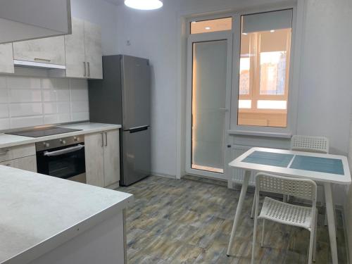 uma cozinha com uma mesa e cadeiras e um frigorífico em Квартира в новострое em Odessa