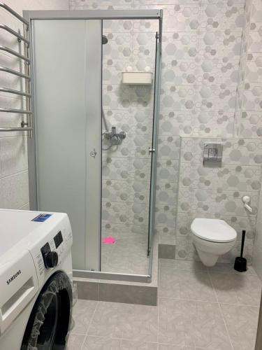 La salle de bains est pourvue de toilettes et d'une douche avec une porte en verre. dans l'établissement Квартира в новострое, à Odessa